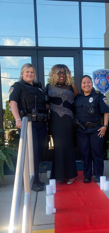 Sharrieffa Barksdale in an evening gown greeted by two City of Harriman police officers
